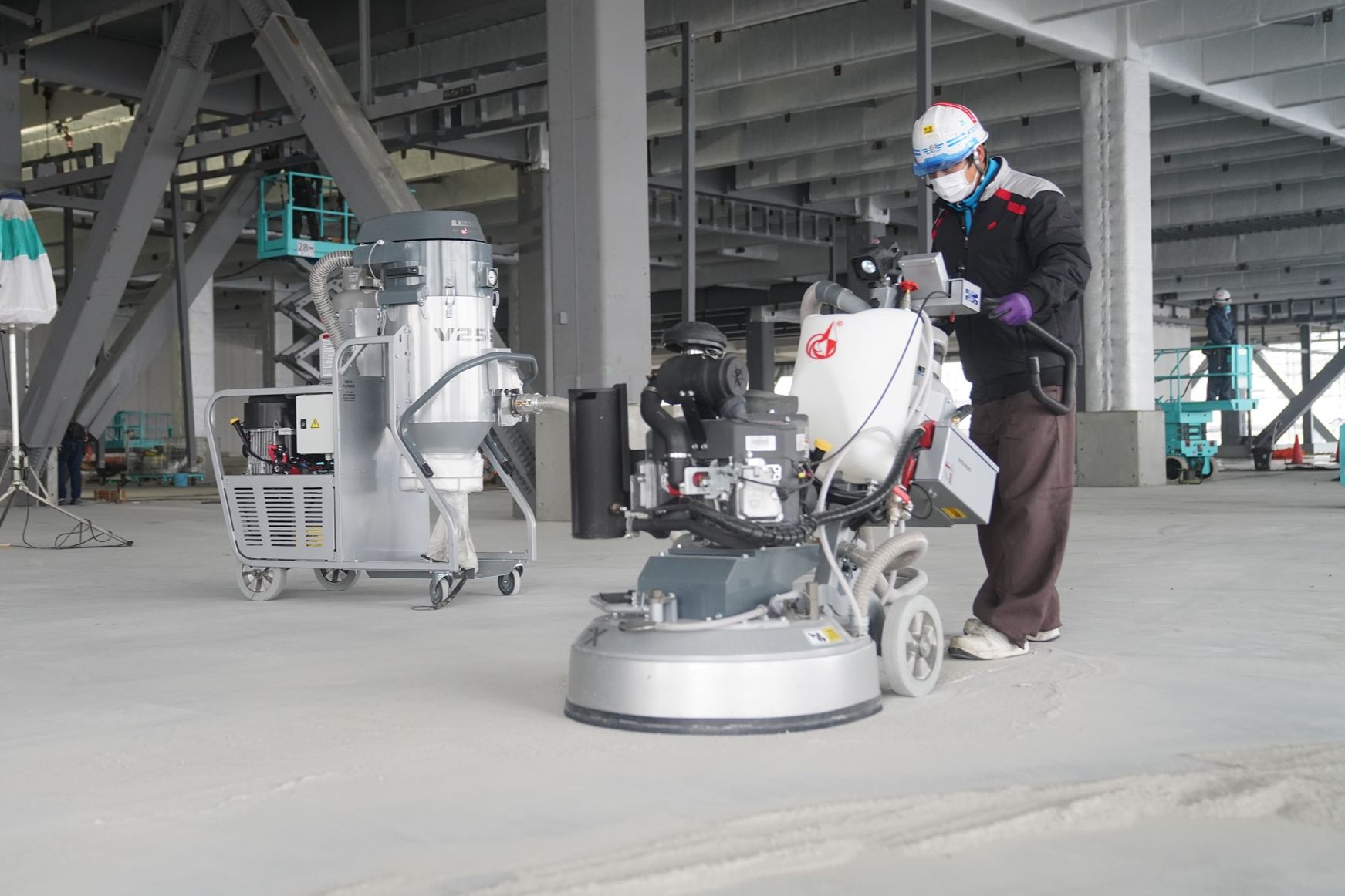 研磨機と集塵機を使用してコンクリート床を施工するフロアエージェントの職人